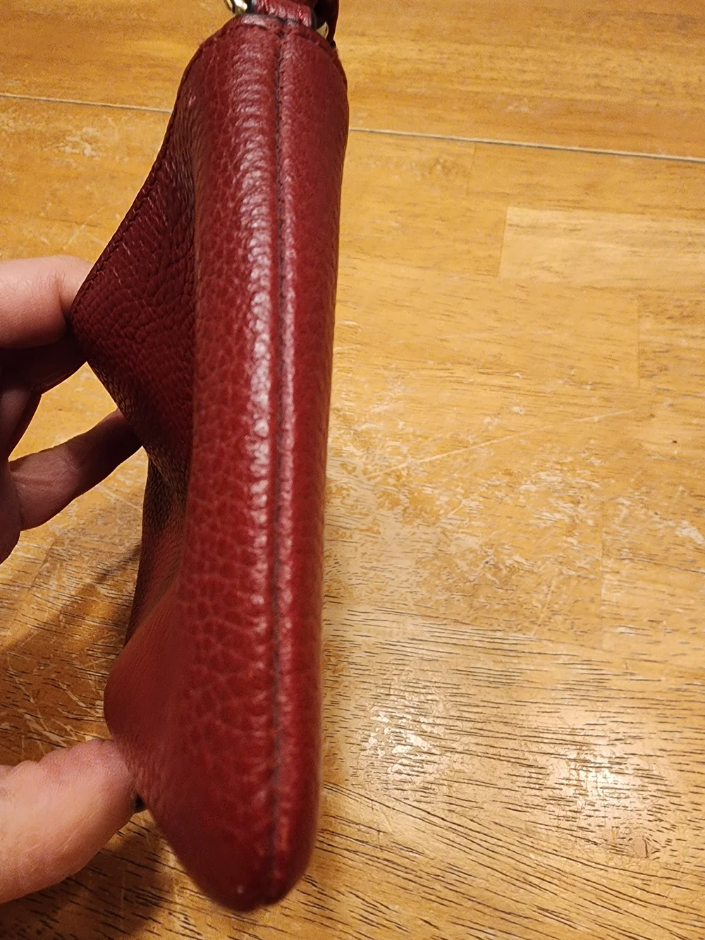 red polished pebble leather Coach wristlet, featuring gold-tone hardware